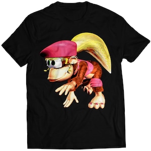 Puede incluir: Camiseta negra con una imagen de dibujos animados de una mona con un sombrero rosa y un atuendo rosa y marrón.