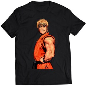 Könnte beinhalten: Schwarzes T-Shirt mit einem Grafikdruck eines blonden Mannes in einem roten Karate-Gi. Der Mann schaut nach links und hat einen ernsten Gesichtsausdruck.