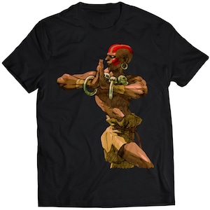 May include: A black t-shirt with a colorful illustration of a character from a video game. The character is a muscular man with red hair and a red headband. He is wearing a green and brown loincloth and has a serious expression on his face.