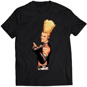 Könnte beinhalten: Schwarzes T-Shirt mit einem Grafikdruck eines blonden Mannes mit einer stacheligen Frisur, der eine schwarze Lederjacke und eine schwarze Hose trägt. Er zeigt mit seiner rechten Hand und hat ein Tattoo auf seinem linken Arm.