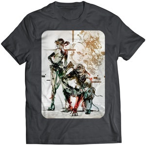 May include: A dark grey t-shirt featuring a graphic print of three characters from a video game. The characters are a woman with a gun, a man with a robotic arm, and a man with a helmet. The graphic is in a digital style with a white background.
