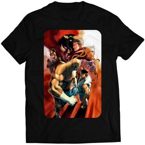 May include: Black t-shirt with a colorful illustration of characters from a fighting video game. The characters are in various poses, some with their fists raised. The background is a mix of red and orange.