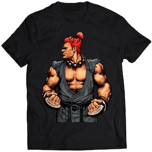 May include: A black t-shirt with a graphic print of a red-haired, muscular character with a black belt and a beaded necklace. The character is in a fighting stance with his fists clenched.