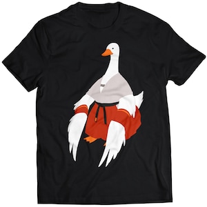 May include: A black t-shirt with a white goose wearing a karate uniform and red boxing gloves. The goose has a white beak and a white stripe on its head.