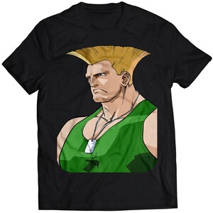 Op de afbeelding: Zwart T-shirt met een cartoonillustratie van een gespierde man met blond haar, die een groene tanktop en een zilveren hondenpenning draagt.