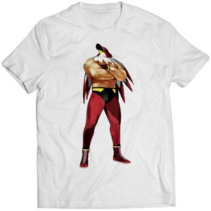May include: White t-shirt with a graphic of a wrestler wearing a red and yellow costume with a bird head.