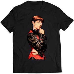 Könnte beinhalten: Schwarzes T-Shirt mit einer bunten Illustration einer Frau mit kurzen, dunklen Haaren, die eine rot-schwarze Jacke trägt.