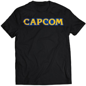 May include: Black t-shirt with the word "CAPCOM" in yellow letters with a blue outline.