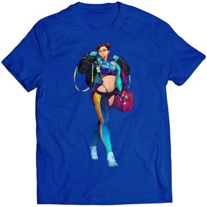 Op de afbeelding: Een blauw t-shirt met een afbeelding van een vrouw in een blauw en geel outfit, die een rode tas draagt. De vrouw draagt een geel hoofdband en een zonnebril.