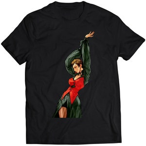 Könnte beinhalten: Ein schwarzes T-Shirt mit einem Grafikdruck einer Frau in einem roten und grünen Outfit. Die Frau posiert mit ihrem Arm über dem Kopf.