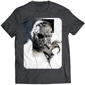 May include: A dark grey t-shirt with a white square graphic featuring a black and white illustration of a man with a beard and an eyepatch. The man is wearing a white shirt and has a cigarette in his mouth.