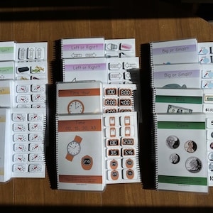 May include: A set of ten colorful educational activity books with spiral binding. Each book features a different theme, such as "Top or Bottom", "Left or Right", "Big or Small", "More or Less", "Time", "Bills", and "Coins". The books are filled with colorful illustrations and activities to help children learn.