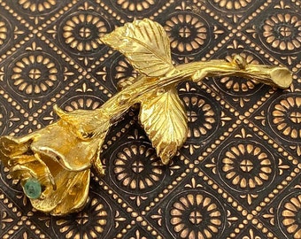 Golden rose brooch with small green stone