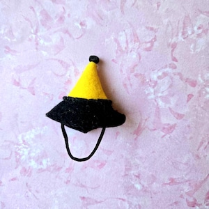 May include: A small yellow and black felt party hat with a black string.