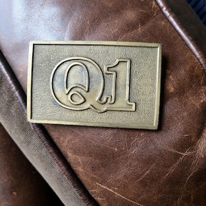 Hebilla de cinturón vintage Q1 de los años 70 y 80, metal en tono latón dorado, rectángulo, letra Q 1. Trabajo de calidad n.° 1, década de 1980, primer trimestre fiscal.