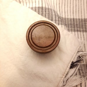 May include: A round, wooden, brown lid with concentric circles.