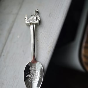 May include: A silver-toned souvenir spoon featuring a three-dimensional lighthouse topper labeled Whitefish Point. The bowl of the spoon displays an engraved map of Michigan with the text Michigan Water Wonderland and various state landmarks.