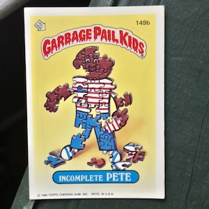 May include: A vintage Garbage Pail Kids trading card featuring "Incomplete Pete." The card has a yellow background with a cartoon figure made of puzzle pieces. The figure is brown, blue, and white. The card's title is in a blue box.