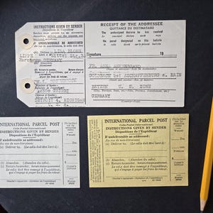 May include: Three vintage international parcel post tags with instructions for the sender and a receipt for the addressee. The tags are yellowed with age and have black text. The receipt is white with black text. The text on the tags includes "Instructions Given by Sender" and "Dispositions de l'Expéditeur". The text on the receipt includes "Receipt of the Addressee" and "Quittance du Destinataire".
