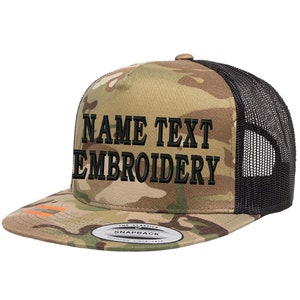 Op de afbeelding: Een camouflage trucker cap met een zwarte mesh achterkant. De pet heeft zwarte geborduurde tekst die "NAME TEXT EMBROIDERY" zegt.