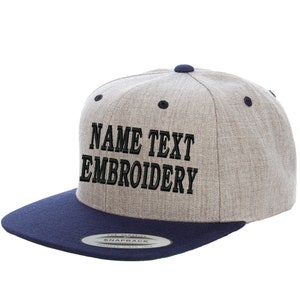 Könnte beinhalten: Eine graue und marineblaue Baseballkappe mit schwarzem Sticktext, der "NAME TEXT EMBROIDERY" lautet.
