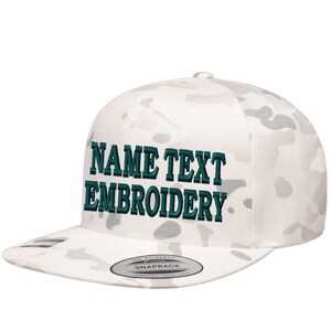 Peut inclure: Casquette de baseball blanche à motif camouflage avec un texte brodé en turquoise foncé qui dit "NAME TEXT EMBROIDERY".