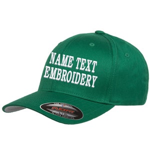 Może przedstawiać: Zielona czapka bejsbolówka z białym haftem, na którym widnieje napis "NAME TEXT EMBROIDERY". Czapka ma czarną i czerwoną metkę Flexfit z napisem "The Original Flexfit L/XL It Fits Your Life".