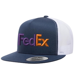 May include: A navy blue and white trucker hat with the FedEx logo embroidered in purple and orange. The hat has a flat brim and a snapback closure. The text "FedEx" is prominently displayed on the front.