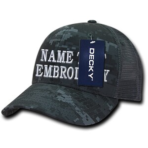 Puede incluir: Una gorra de camionero de camuflaje negro y gris con un texto bordado en blanco que dice "NAME & EMBROIDERY". Una etiqueta azul con la palabra "DECKY" está unida a la gorra.