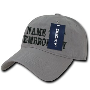 Puede incluir: Gorra de béisbol gris con bordado negro que dice "NAME & EMBROIDERY". Una etiqueta azul con la palabra "DECKY" está unida a la gorra.