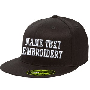 Puede incluir: Gorra de béisbol negra ajustada con texto bordado en blanco que dice "NAME TEXT EMBROIDERY". La gorra tiene una etiqueta verde y blanca que dice "310 Fitted Flexfit Tech".