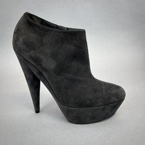 May include: Gray suede ankle boots with a high platform heel and a pointed toe.