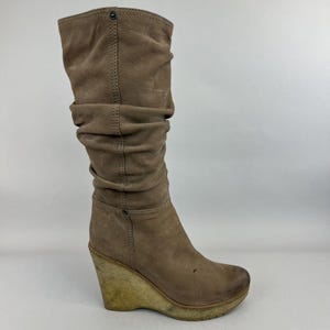 May include: Brown suede wedge boots with a slouchy shaft and a platform sole.