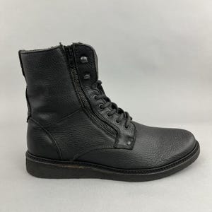 May include: Black leather combat boot with a side zip and lace-up fastening. The boot has a textured finish and a rounded toe. The sole is dark and the boot is mid-calf height.