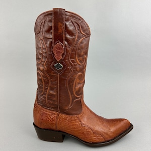 May include: A brown leather cowboy boot with intricate stitching and a pointed toe. The boot features a textured vamp and a decorative emblem near the top. The boot's shaft is approximately 12 inches tall.