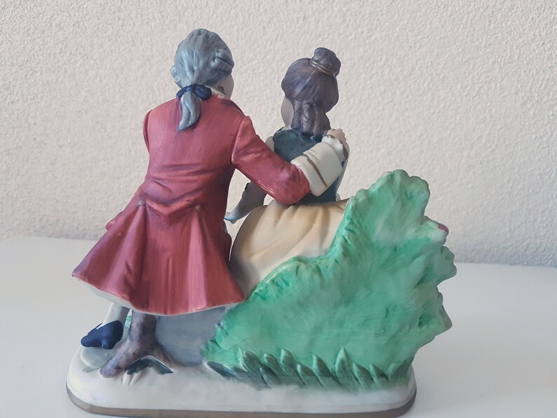 Large vintage porcelain figurine young Couple with flowers sitting on a rock