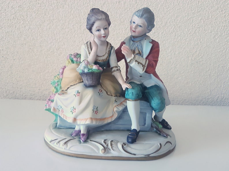 Large vintage porcelain figurine young Couple with flowers sitting on a rock