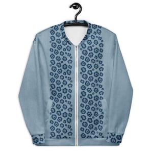 May include: A pale blue bomber jacket featuring a dark blue floral design down the front and on the sleeves. The jacket has a white zip and is suspended from a black hanger.