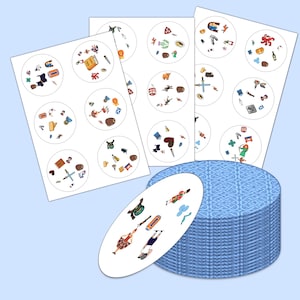 May include: A set of illustrated game cards featuring various colorful objects and characters within circular frames. The cards are white with a blue patterned border, and are stacked next to a deck of blue cards.