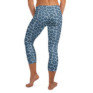 May include: Blue capri leggings with a repeating dark blue floral pattern. The leggings are cropped at the calf and have a high waist. The fabric appears to be a soft, stretchy material.