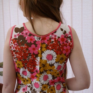 May include: A sleeveless dress with a white background and a floral pattern in shades of pink, red, brown, and yellow.