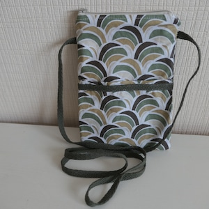 May include: A small crossbody bag with a long adjustable strap. The bag is made of a green, brown and white patterned fabric and has a zipper closure.