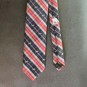 Peut inclure: Une cravate rayée rouge et bleue avec un motif de trompettes dorées. La cravate porte une étiquette indiquant "Made in England".