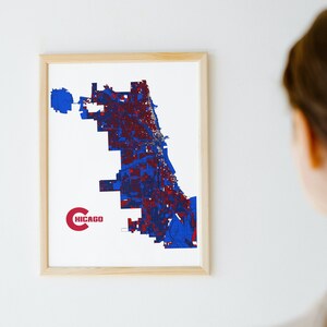 May include: A framed print of a map of Chicago, Illinois. The map is in blue and red colors and the word "CHICAGO" is written in red at the bottom left corner of the map.