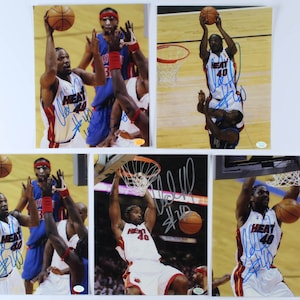 May include: Five signed photographs of a basketball player wearing a red and white jersey with the word "HEAT" and the number "40" on the front. The player is jumping up to dunk a basketball. The photographs are signed in blue ink.