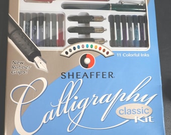 Könnte beinhalten: Ein Sheaffer Calligraphie Classic Kit mit 11 farbigen Tinten, Stiften und Federn. Das Set enthält eine Schritt-für-Schritt-Anleitung und verfügt über neue Gummi-Griffe. Die Box ist blau und weiß mit dem Wort "Calligraphie".