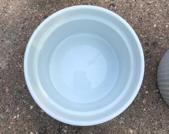 May include: A white ceramic bowl with a smooth, rounded interior. The bowl is empty and has a slight sheen.