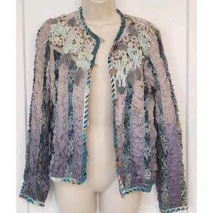 May include: A unique, open-front jacket in shades of lavender, gray, and teal. The jacket features a textured, ruched fabric with decorative lace and ribbon accents. The collar and edges are trimmed with teal ribbon.