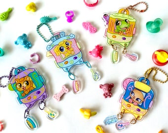 May include: Four colorful charm keychains with cartoon animal characters. Each keychain features a different animal, including a cat, a dog, a frog, and a hamster. The charms are attached to a metal chain with a small, clear plastic charm that has a toothbrush design.