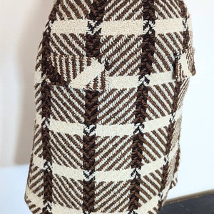May include: A brown and white plaid skirt with a high waist and a flap pocket on the back.